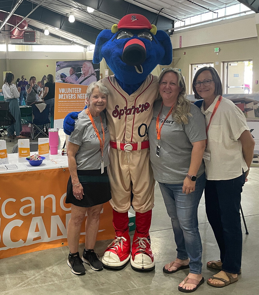 Cancer Can't volunteers working at a conference, posing with a Spokane Mascott
